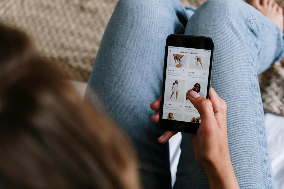 A woman uses her smartphone to shop for clothing online, showcasing digital retail technology.