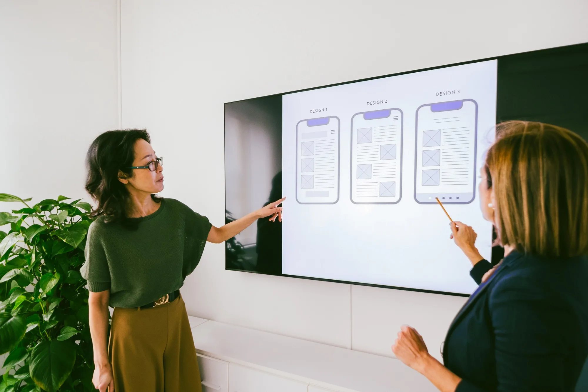 Web designers discussing wireframes on digital screen in office meeting
